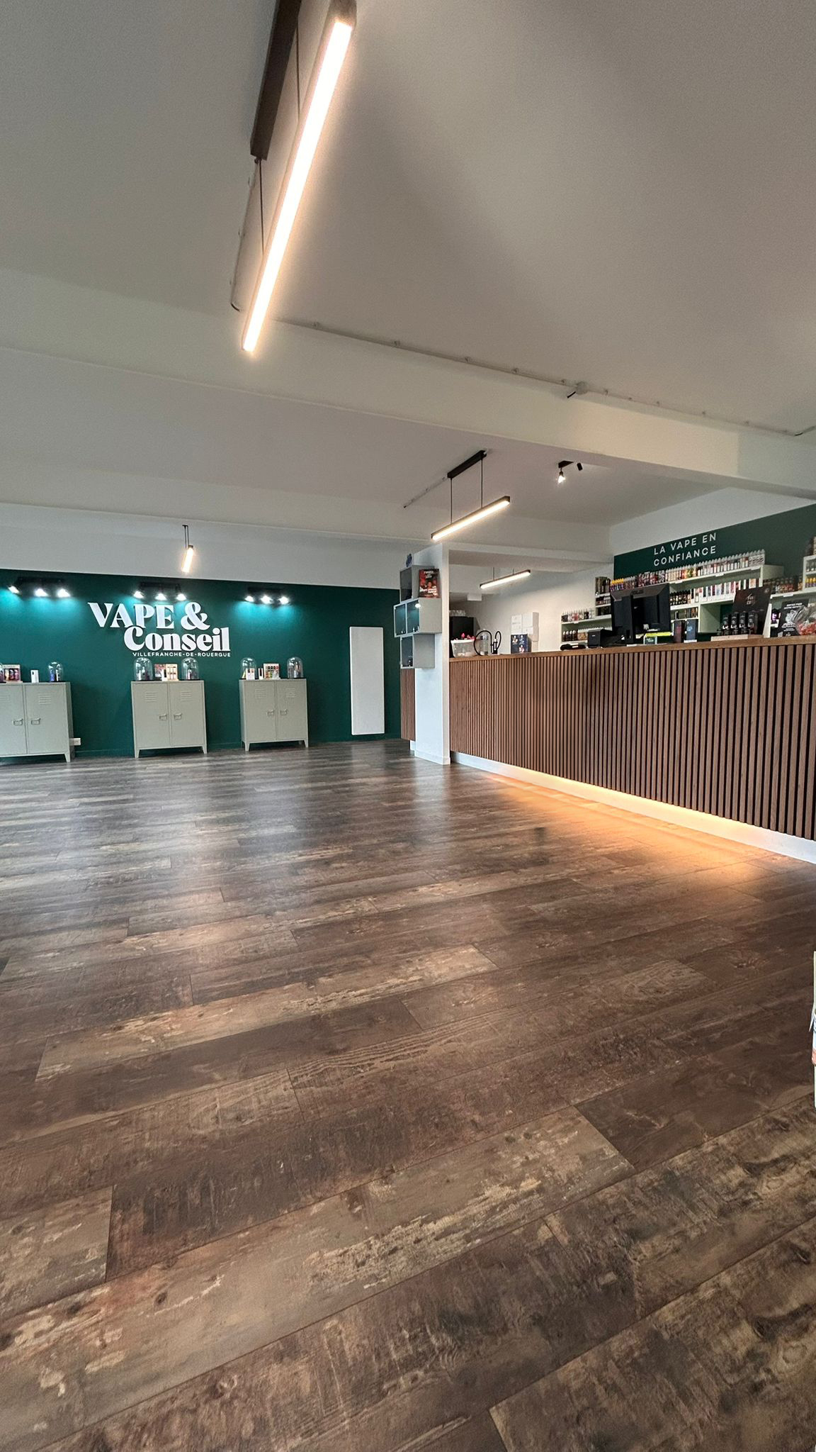 L'intérieur de la boutique, comptoir en bois et mur vert sapin frappé du logo.