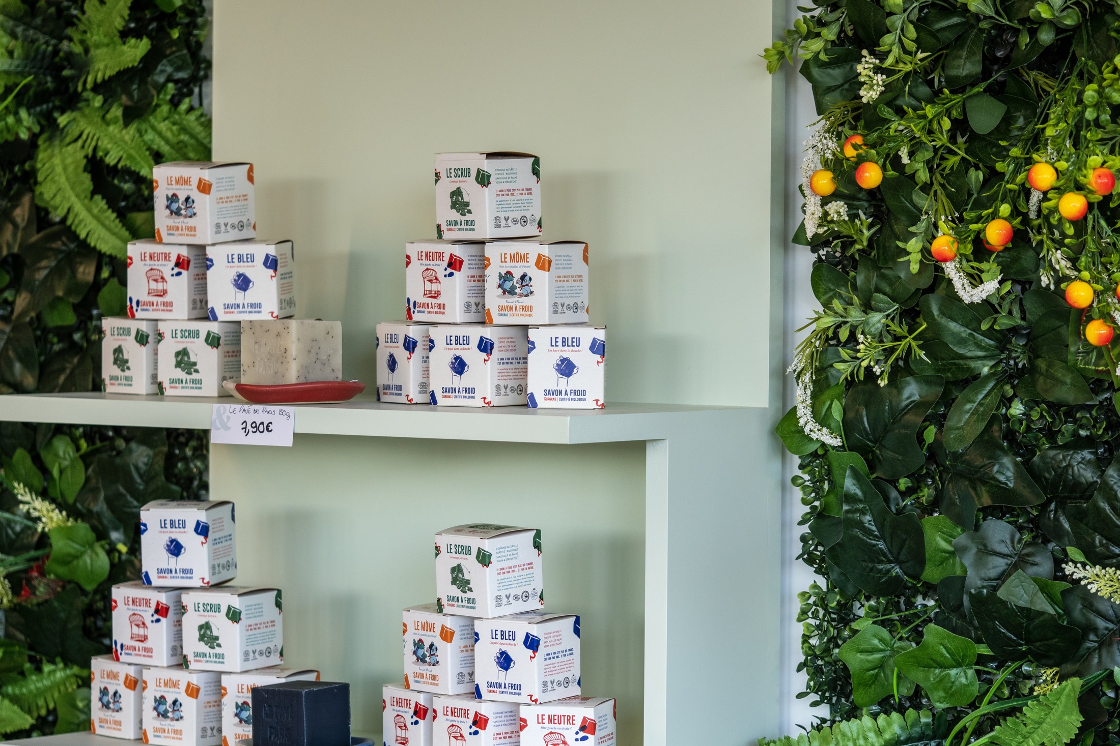Un rayonnage devant le mur végétal, avec ses produits et son étiquette de prix.