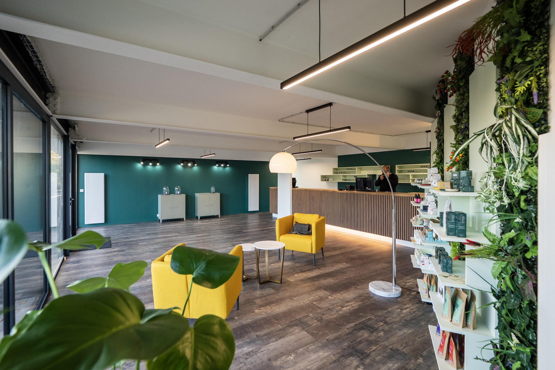 L'espace de la boutique, mur végétal, fauteuils moutarde et comptoir en bois.